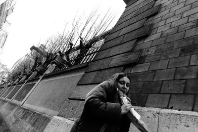 Low angle portrait of woman against building in city