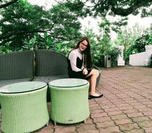 Woman sitting in a smiling while standing against brick wall