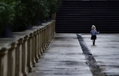 Rear view of woman walking on footpath