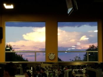 People at dusk against sky seen through window