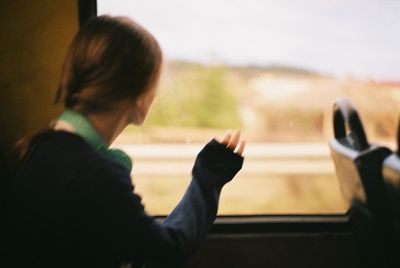 Rear view of boy looking through airplane window