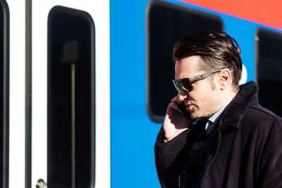 Mid adult businessman talking on the phone at train station.