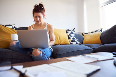 Man using mobile phone while sitting on sofa at home