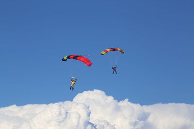 Scenic view of people paragliding against blue sky