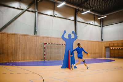 Female handball player running with ball in sports court