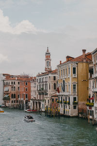 Buildings by canal against sky