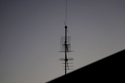 Low angle view of silhouette communications tower against clear sky
