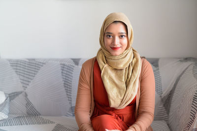 Portrait of smiling young woman sitting on sofa