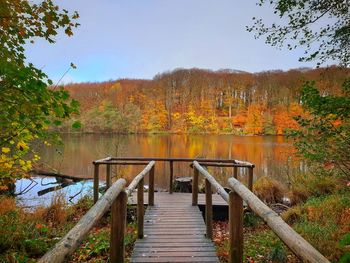 Footbridge over lake against sky during autumn