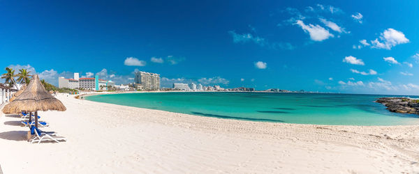 Panoramic view of empty deck chair and luxury hotels by sea