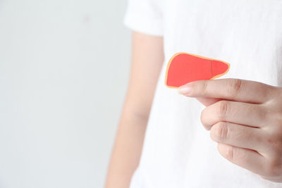 Midsection of woman holding heart shape against white background