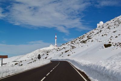 Road amidst snowcapped mountains against sky