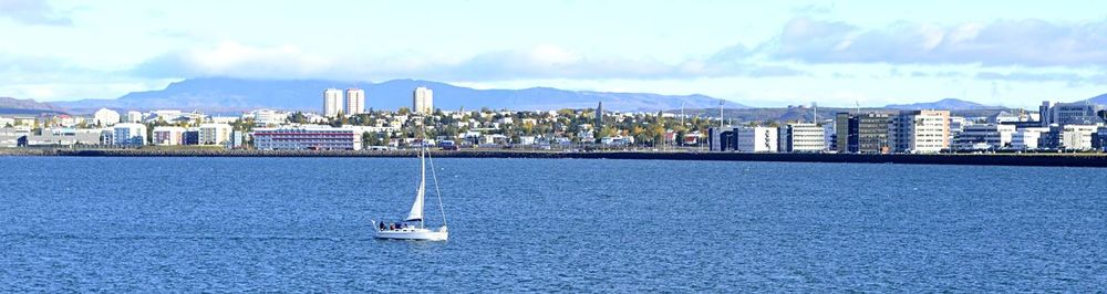 Sailboats in sea against sky in city