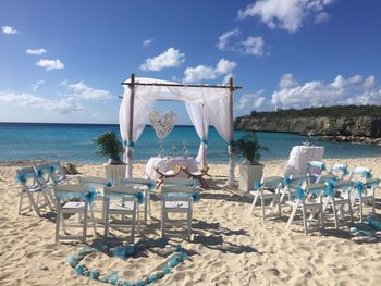 Deck chairs on beach against sky