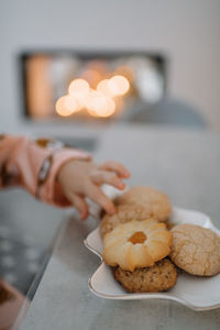 Midsection of woman holding cookies on table at home