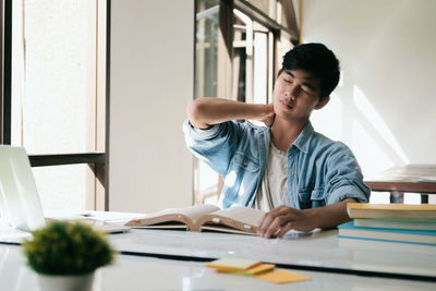 Male student sleeping by table