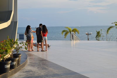 Friends standing at beach against sky