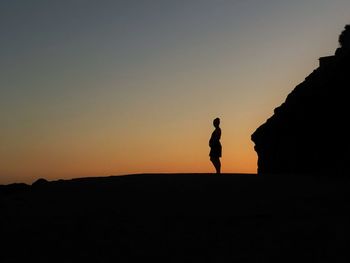 Silhouette man standing against orange sky