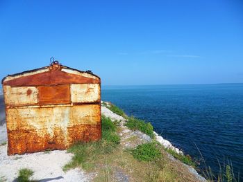 Building by sea against clear blue sky