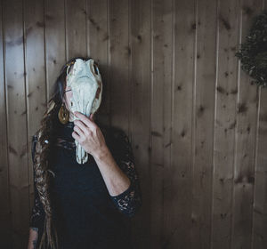 Rear view of woman with arms raised standing against wall