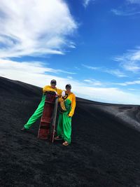 Rear view of men standing on road against sky