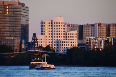 Boat in river by buildings against clear sky