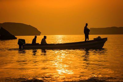 Silhouette of people on boat at sunset