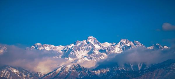 Scenic view of snowcapped mountains against blue sky