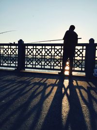 Silhouette of man looking at sea at sunset