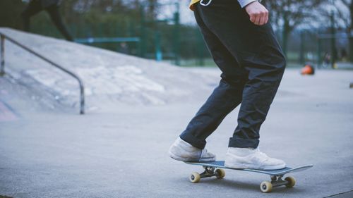 Low section of man skateboarding on concrete