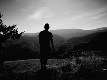 Rear view of man standing on field against sky