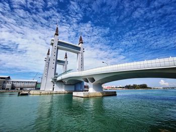 Bridge over river against cloudy sky