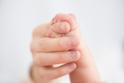 Close-up of parent and baby holding hands