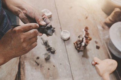 Man molding clay to make ceramics with his hands, artisan working in his workshop, selective focus