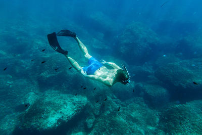 Shirtless young man scuba diving in sea