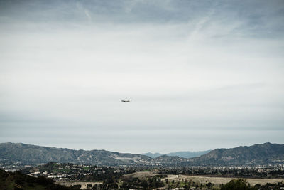 Airplane flying over mountains against sky