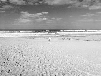 Distant view of woman at beach against sky