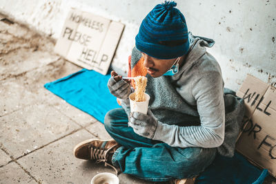 Midsection of man holding ice cream sitting outdoors