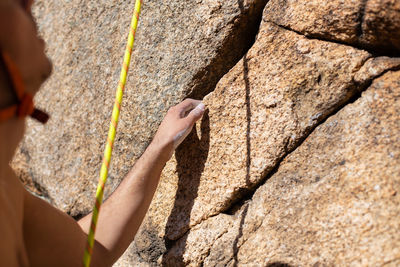 Close-up of shirtless man climbing rock