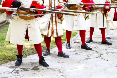 People in costume with weapons standing on footpath