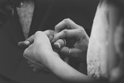 Midsection of bride exchanging ring with groom during wedding