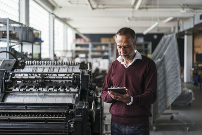 Mature man in a printing shop using digital tablet