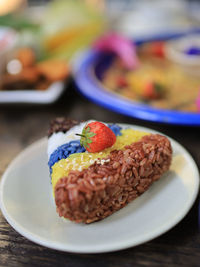 Close-up of 5 colors of rice and strawberry served on table.