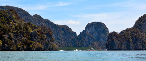 Scenic view of sea by mountains against sky