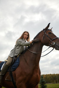 Portrait of woman riding horse on field against sky