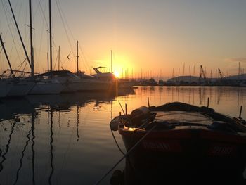 Boats moored at harbor during sunset