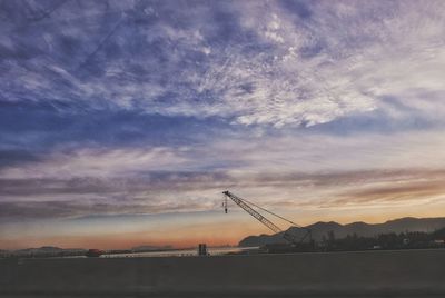 Cranes against sky during sunset