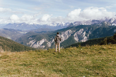 Rear view of man standing on mountain against sky