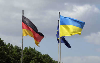 The flags of ukraine, germany, and the eu waving in the wind