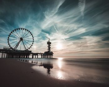 Silhouette ferris wheel at beach during sunset